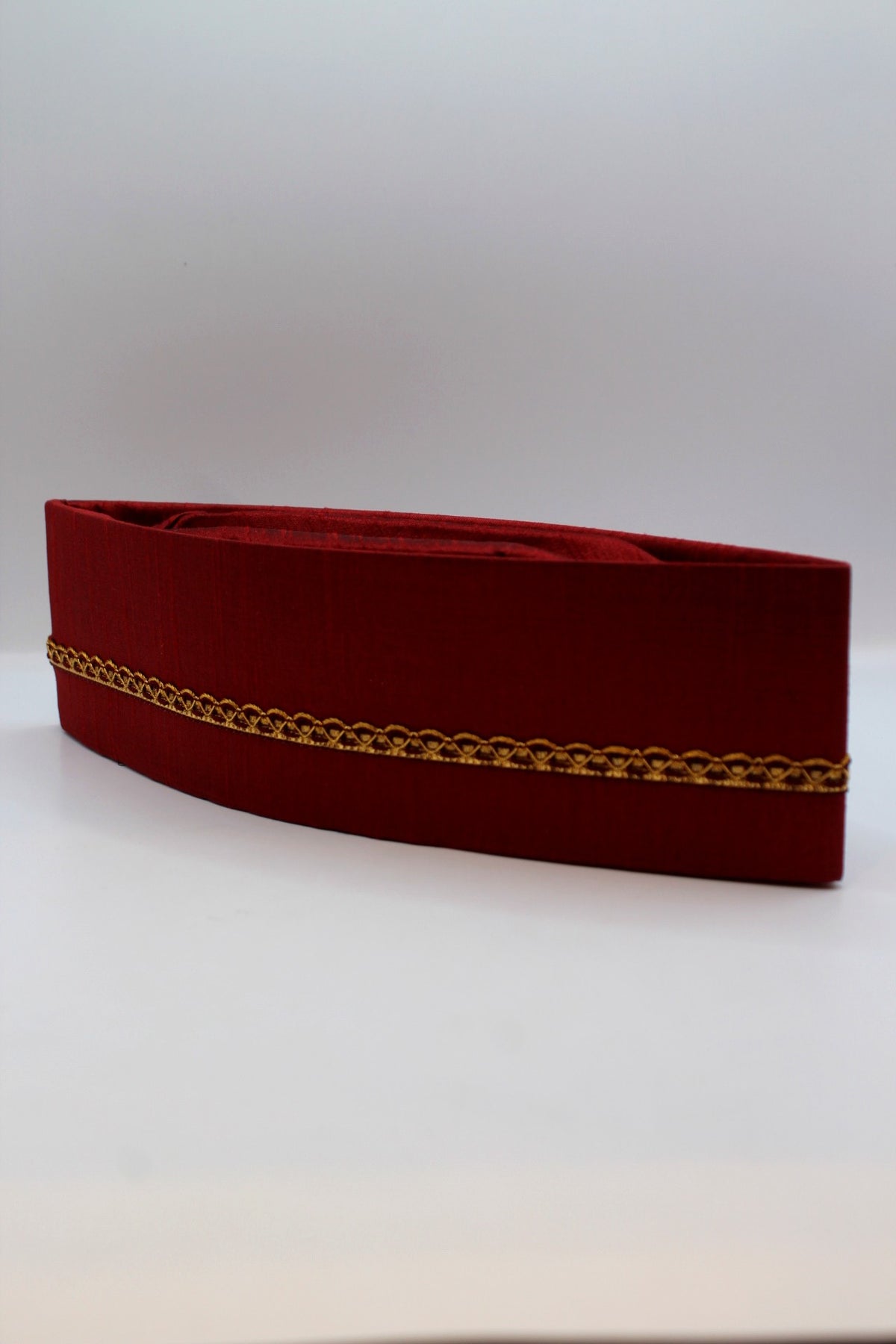 Maroon Gandhi topi with golden border, angled view
