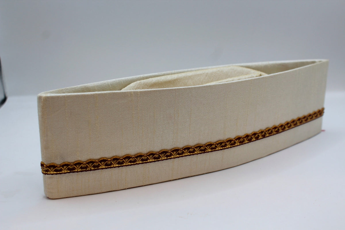 Off-white Gandhi topi with maroon and gold border, angled view