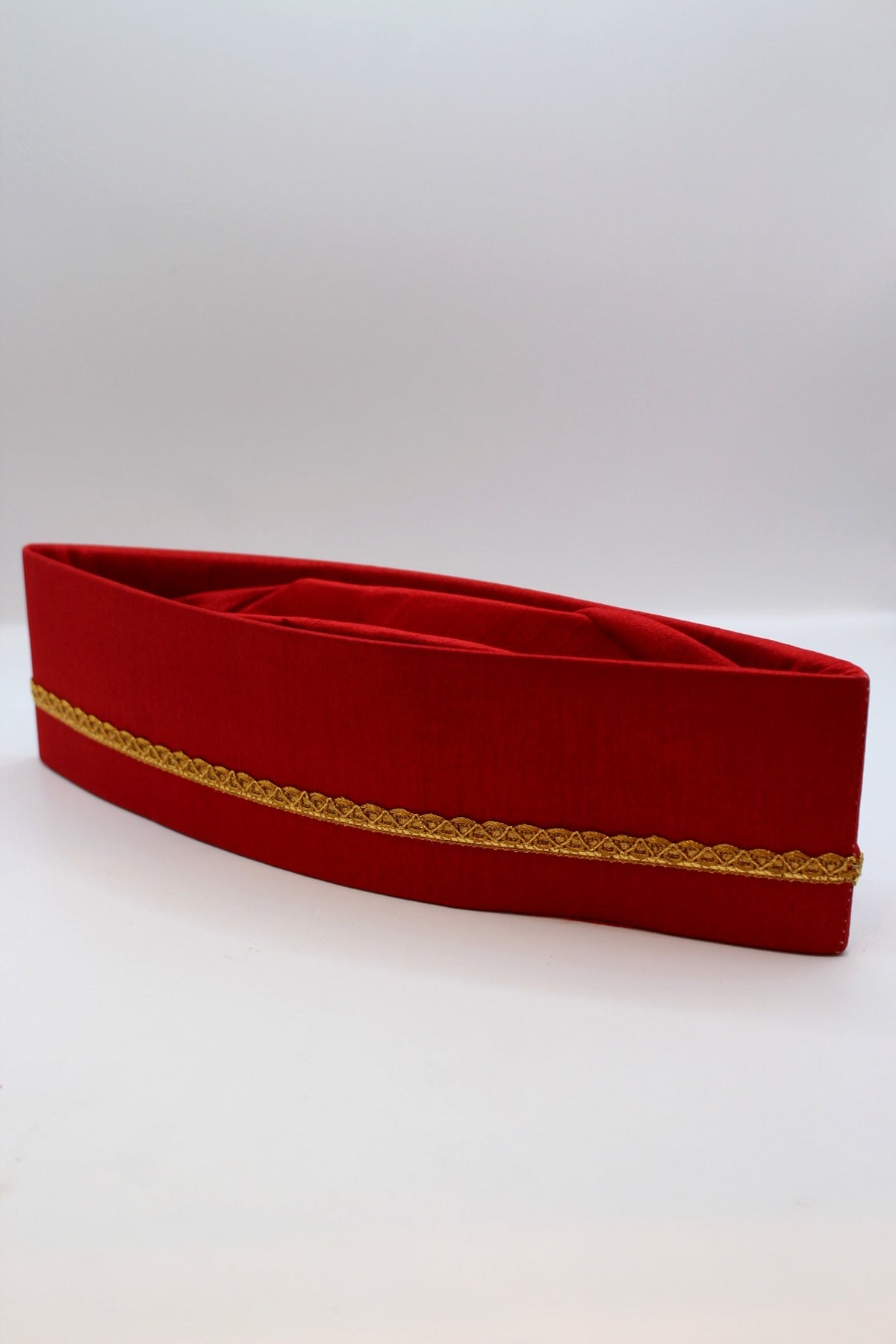 Red Gandhi topi with golden border, angled view