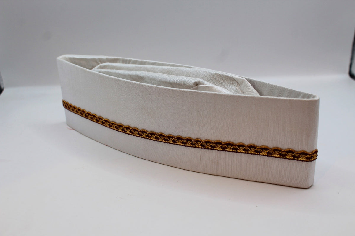 White Gandhi topi with maroon and gold border, angled view