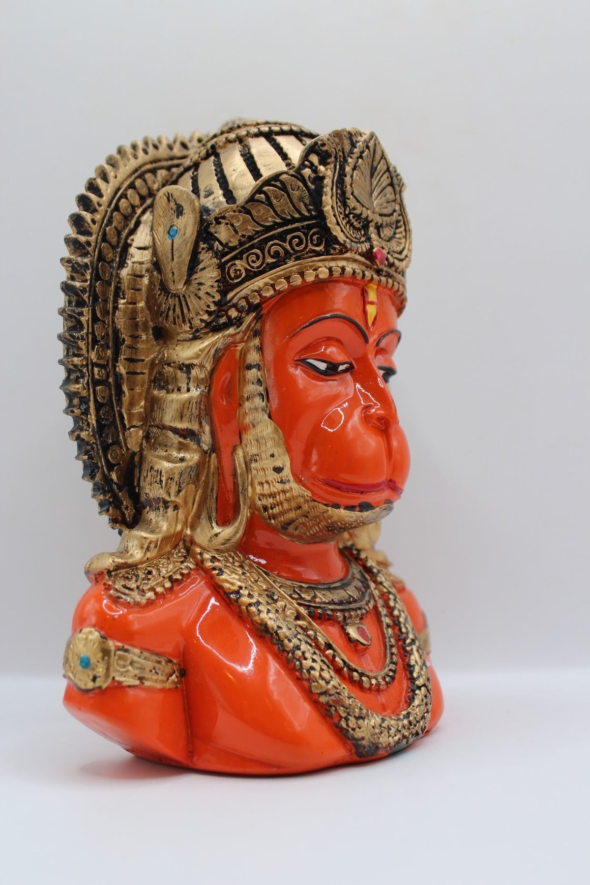 Orange resin Hanuman bust with gold crown, left side view