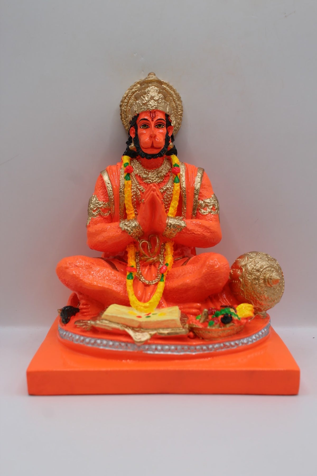 Orange resin Hanuman murti seated in prayer, front view