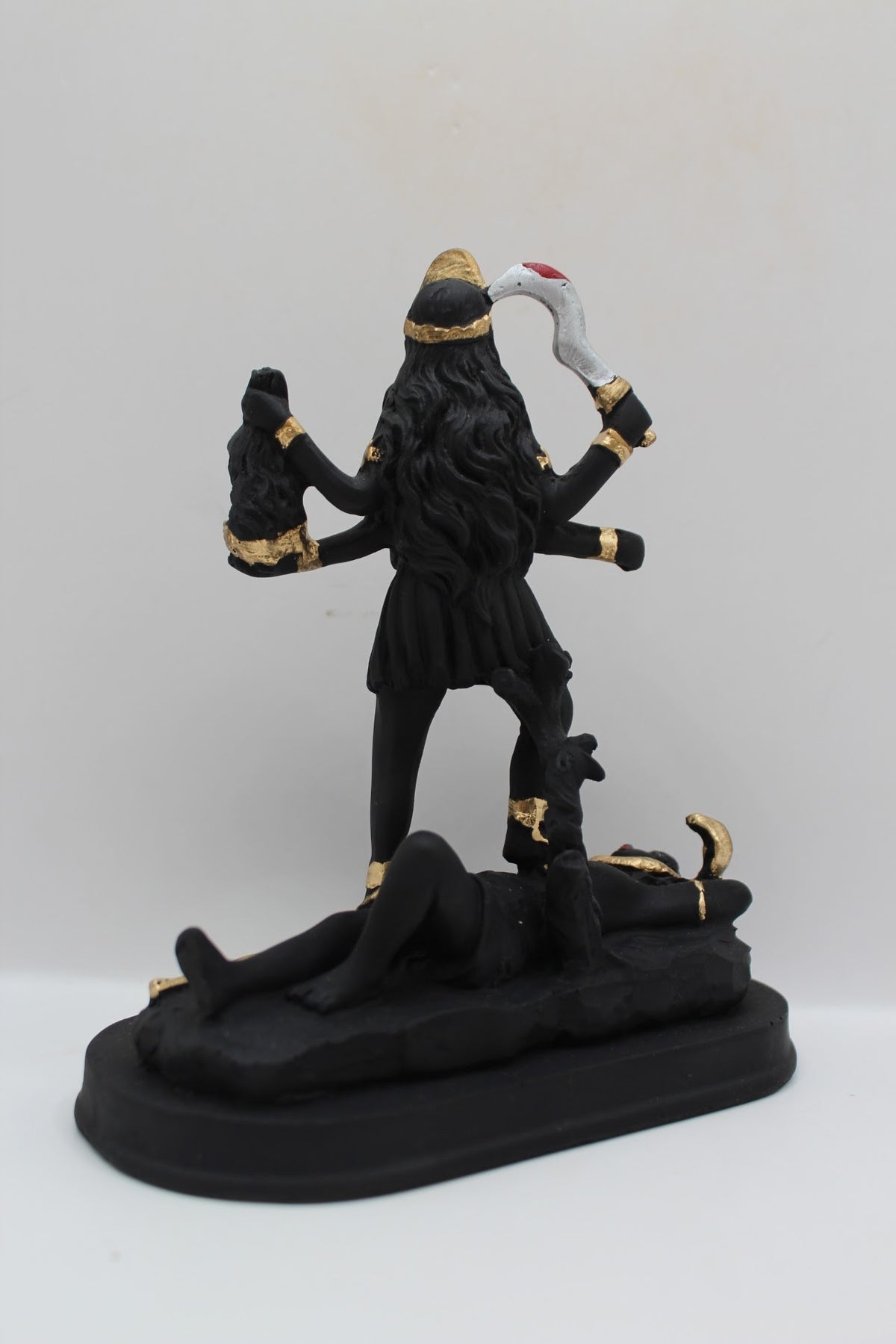 Black and gold resin Kali Mata murti standing on Shiva, back view