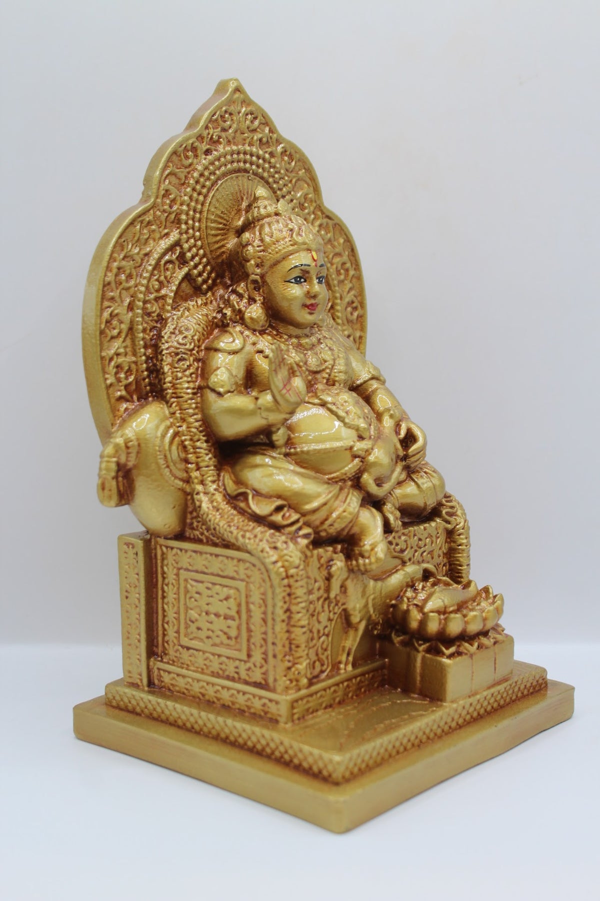 Gold resin Kuber murti seated on a throne, left side view