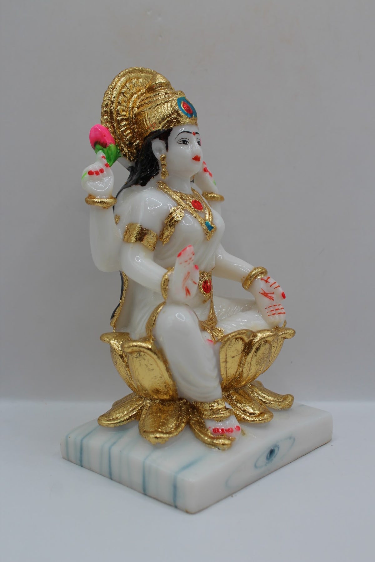 White and gold resin Laxmi murti on a gold lotus, left side view