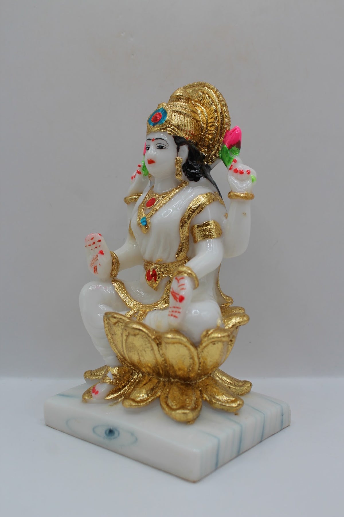White and gold resin Laxmi murti on a gold lotus, right side view