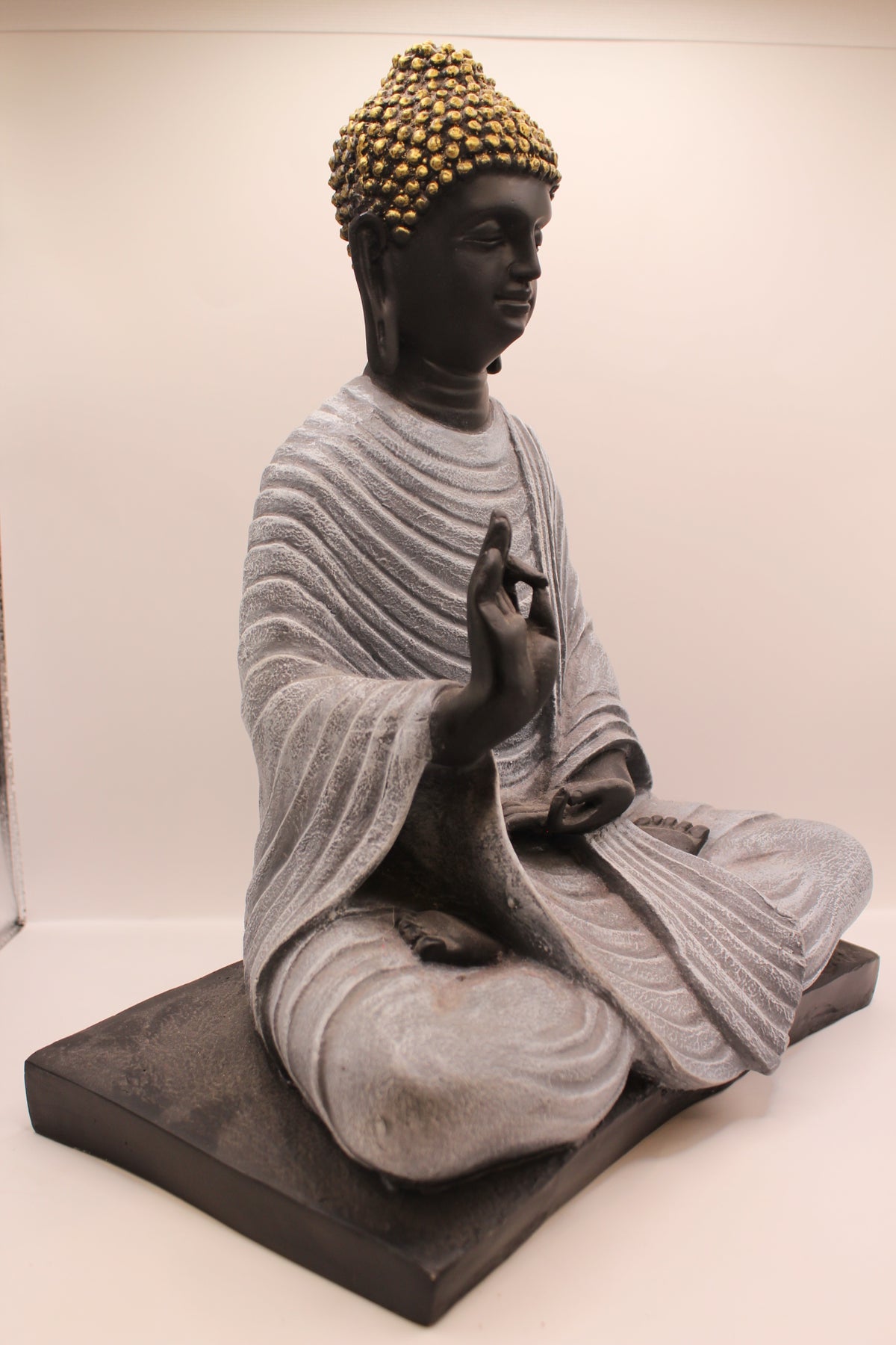 Charcoal grey Buddha statue on base, left side