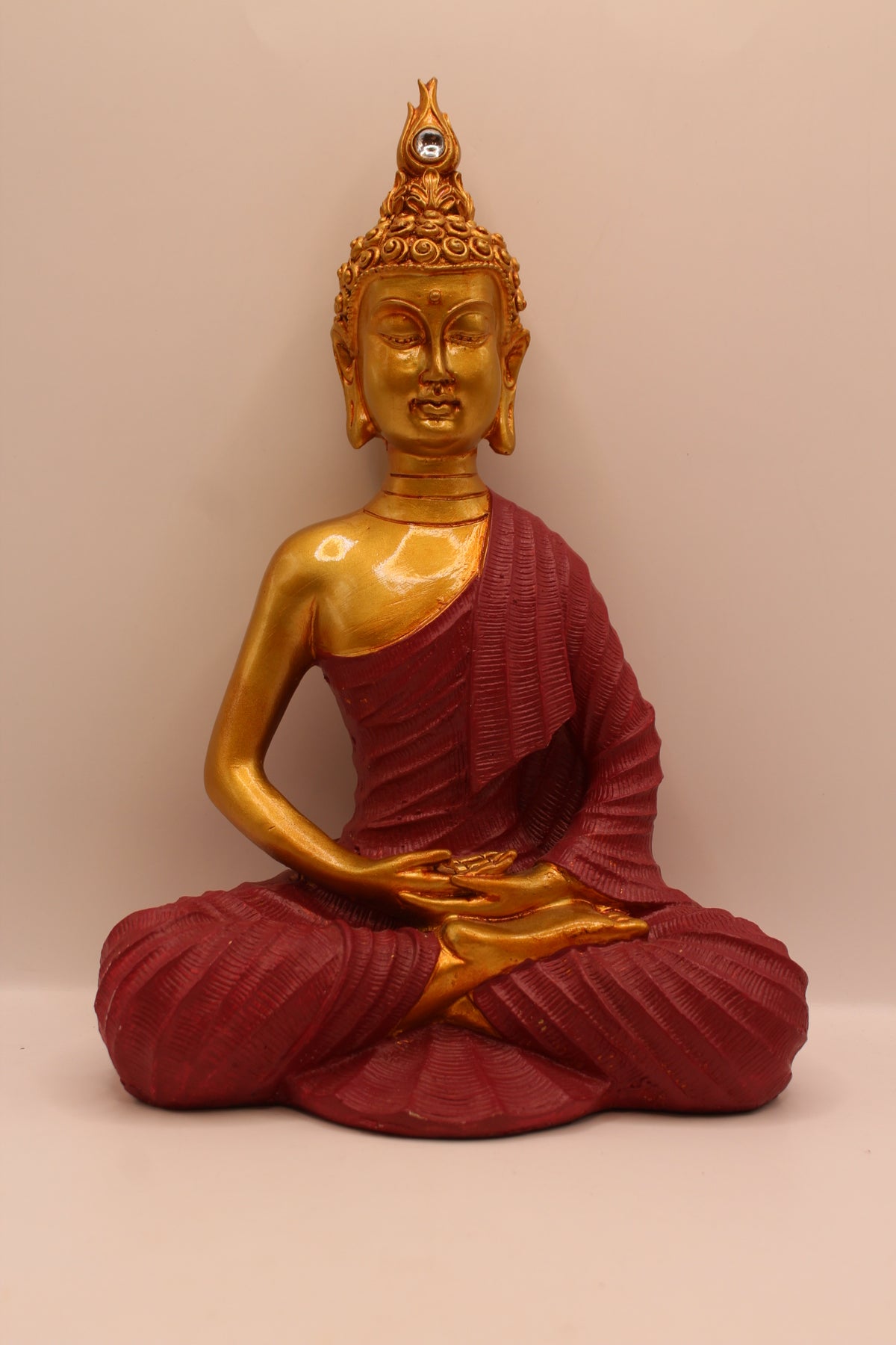 Small meditating Buddha statue, gold with maroon robe, front