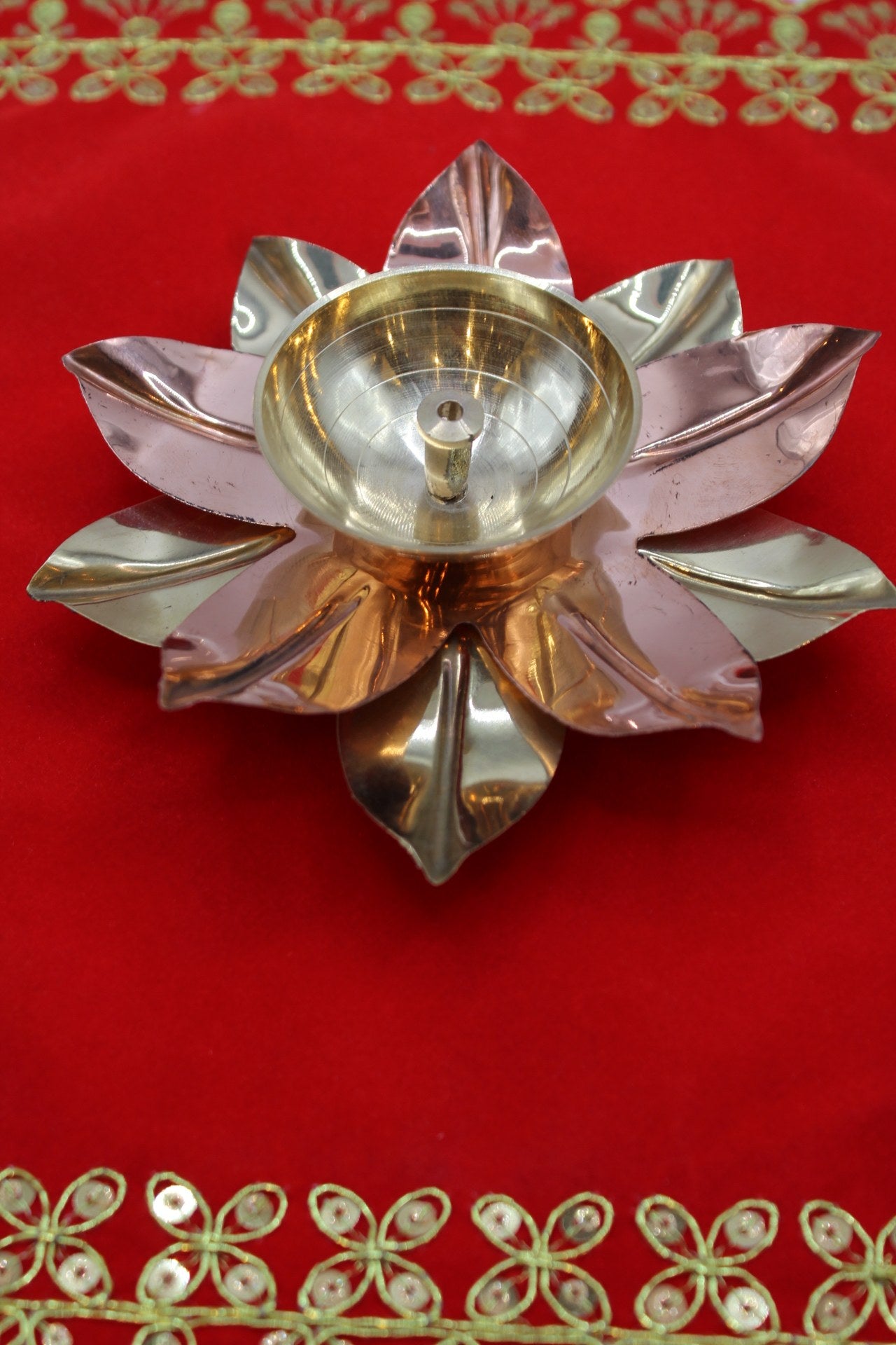 Lotus diya with alternating brass and copper petals around a deep oil well