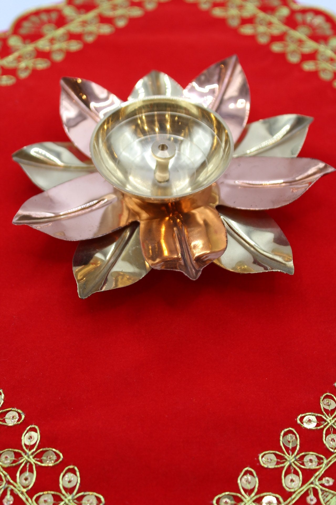 Lotus diya with alternating brass and copper petals around a deep oil well