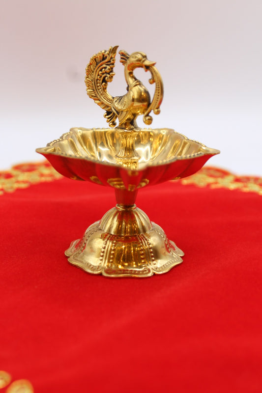 Solid brass peacock diya with a scalloped bowl raised on a fluted pedestal