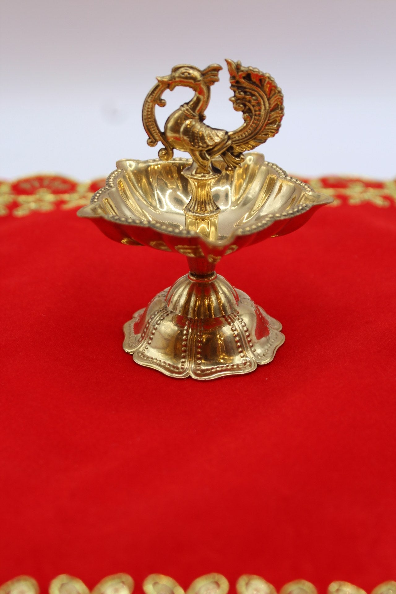 Solid brass peacock diya with a scalloped bowl raised on a fluted pedestal