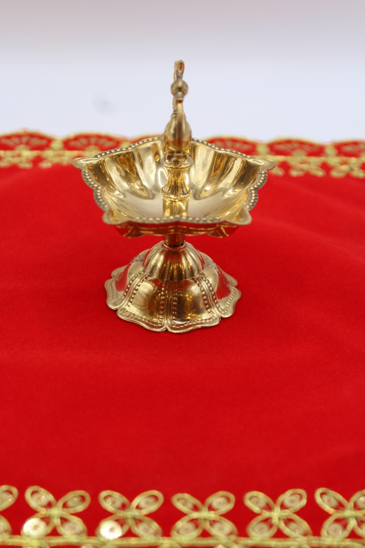 Solid brass peacock diya with a scalloped bowl raised on a fluted pedestal
