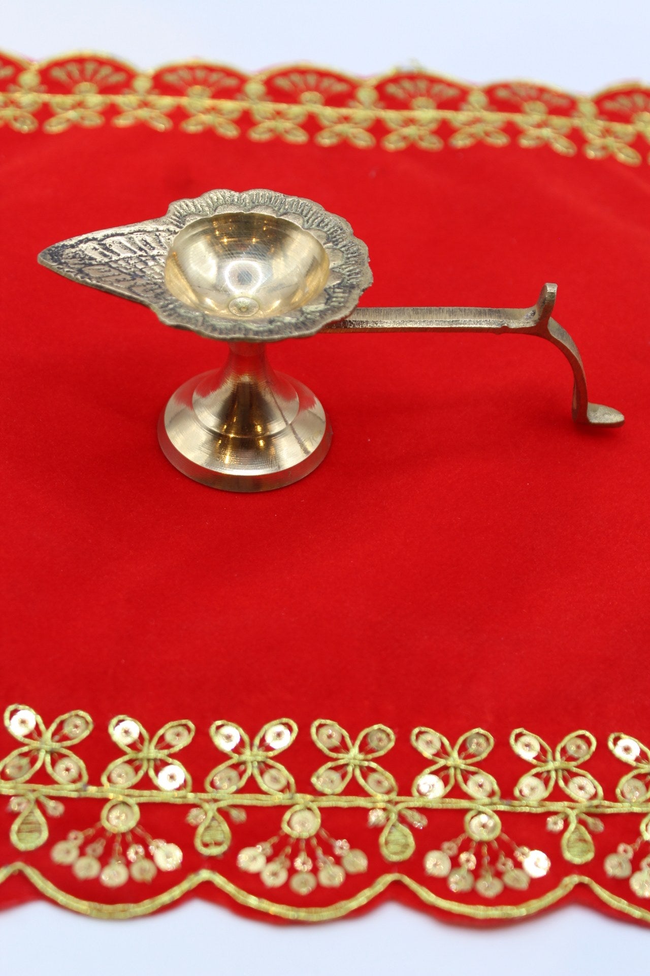 Small footed brass aarti diya with a long side handle and pierced back plate