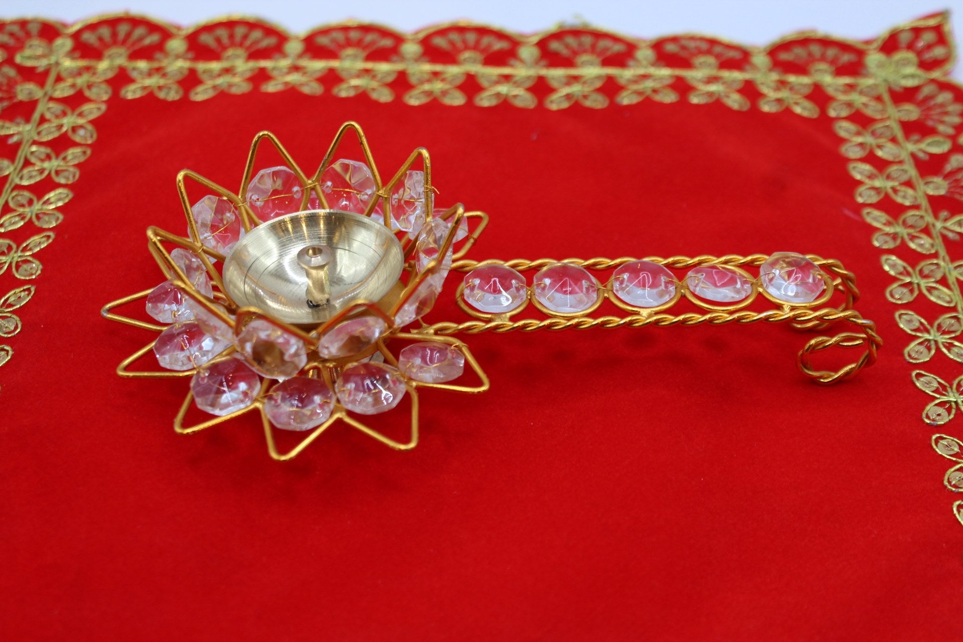 Gold-tone lotus aarti diya set with faceted pink stones and a jewelled handle
