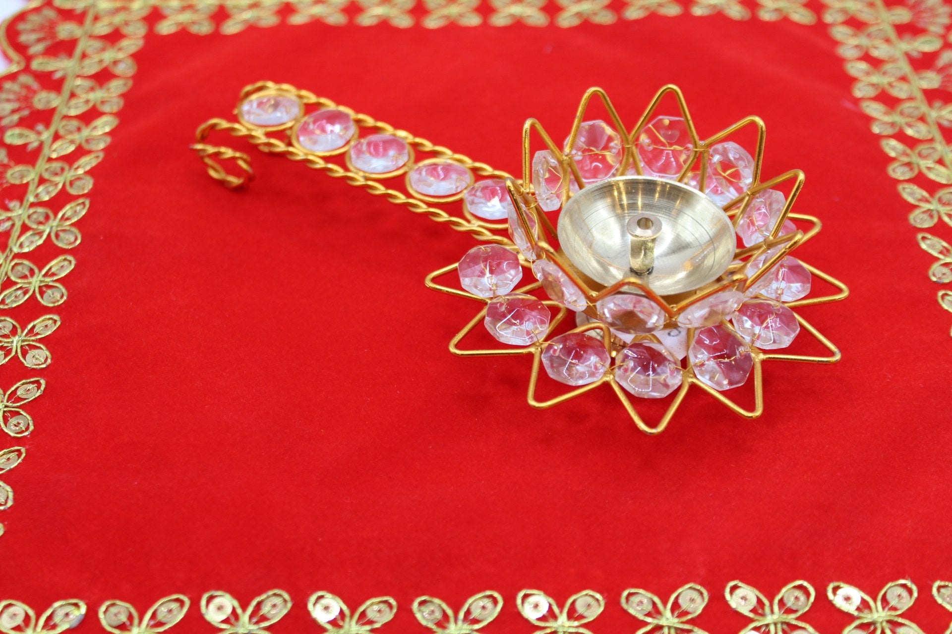 Gold-tone lotus aarti diya set with faceted pink stones and a jewelled handle