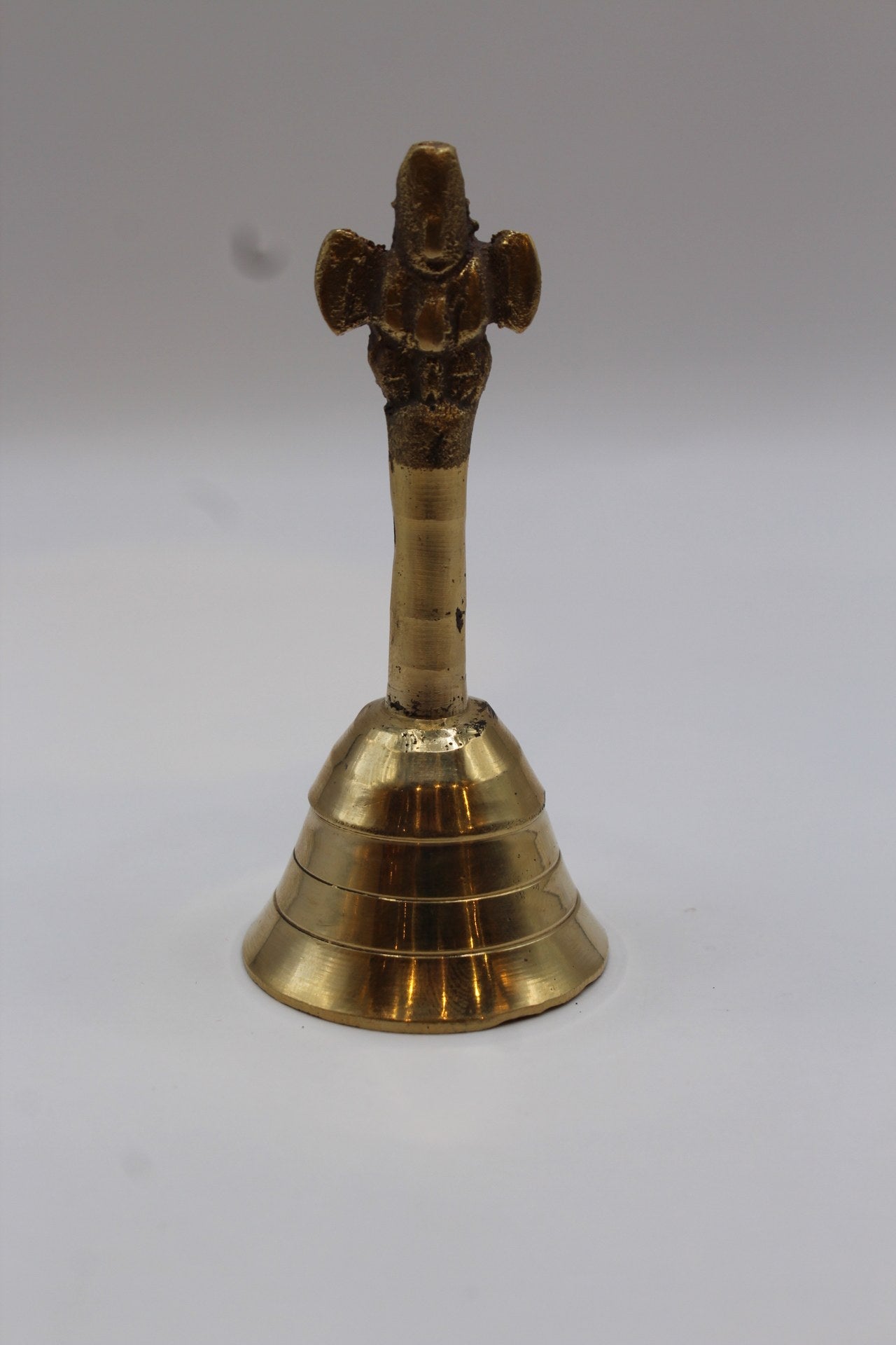Solid brass pooja bell with a stepped skirt and cast handle