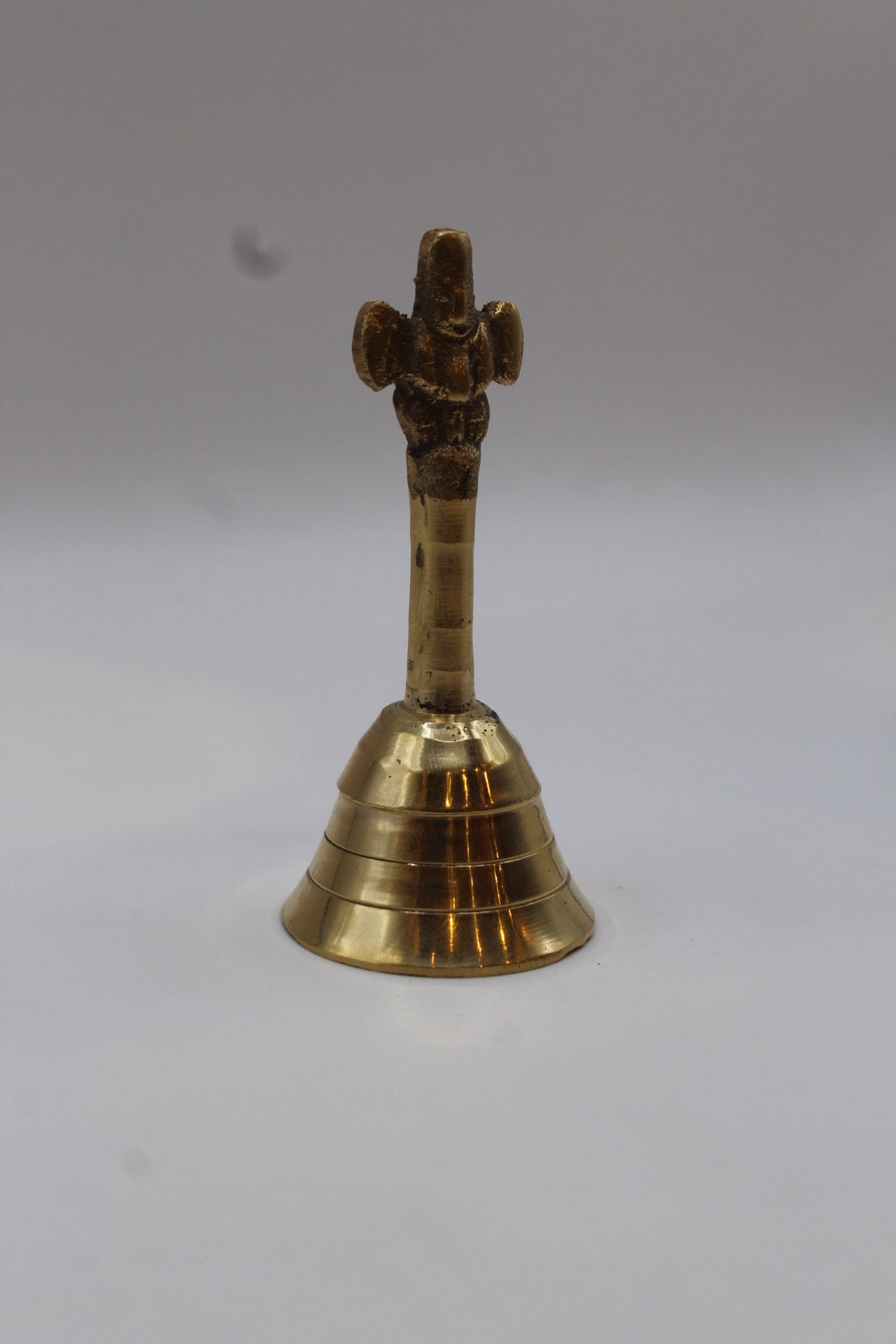 Solid brass pooja bell with a stepped skirt and cast handle