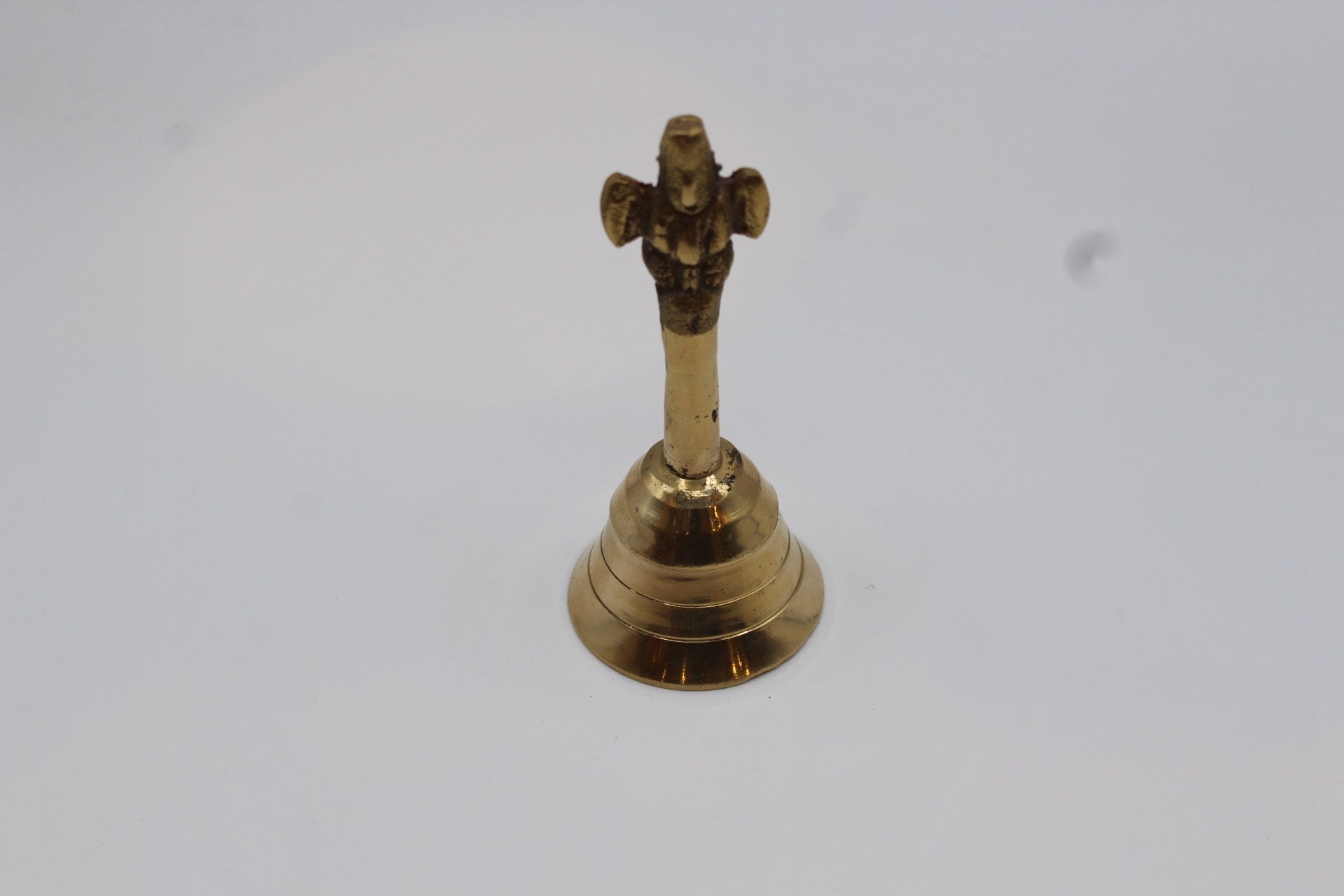 Solid brass pooja bell with a stepped skirt and cast handle