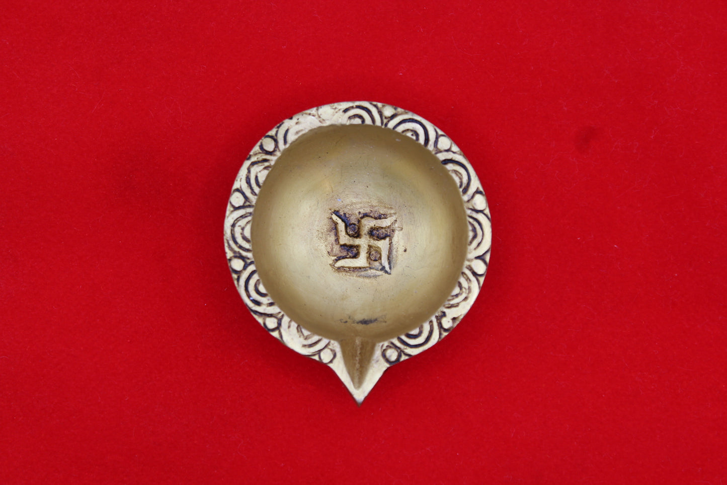 Brass diya seen from above, swastik in the well