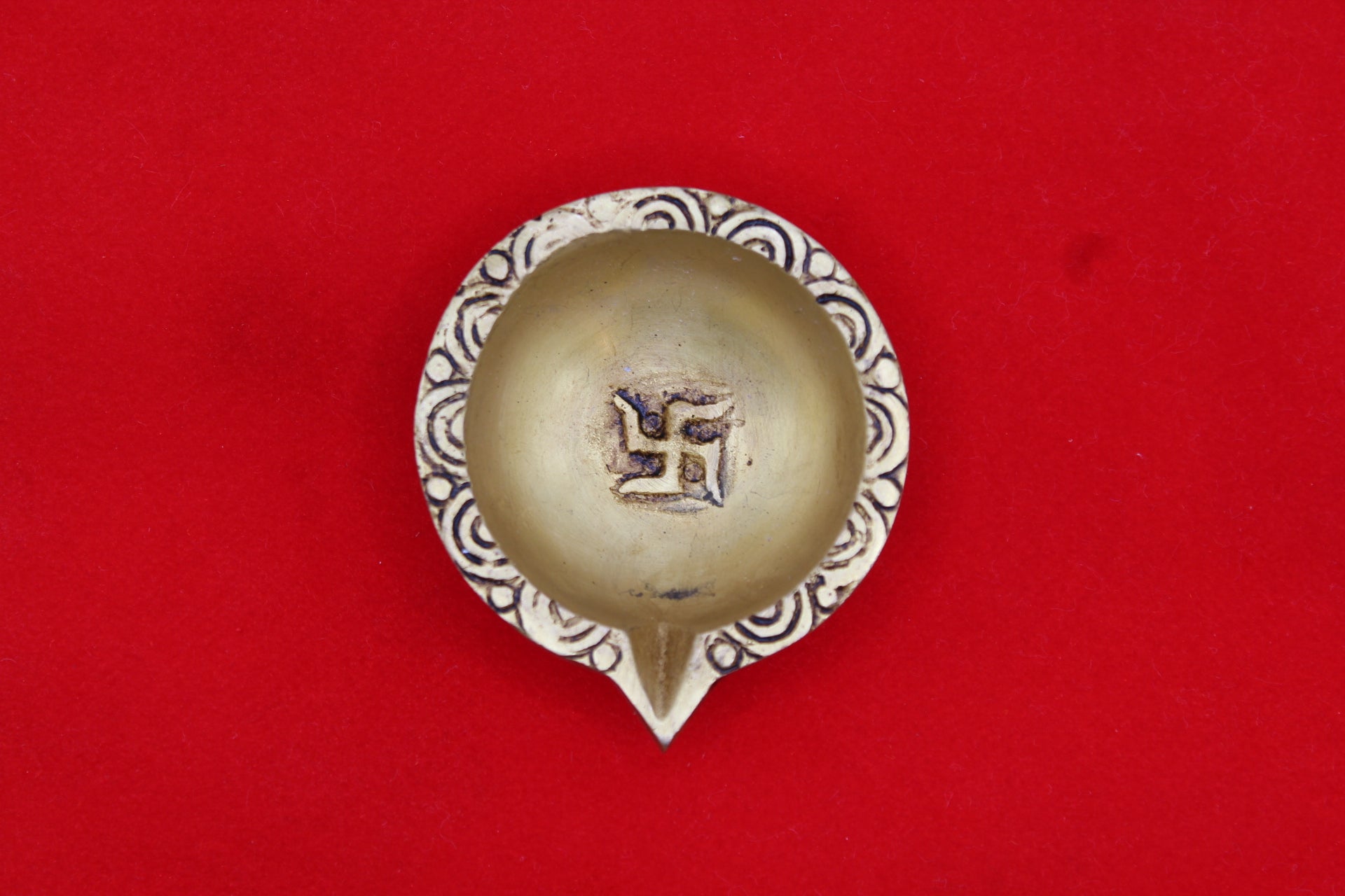 Brass diya seen from above, swastik in the well