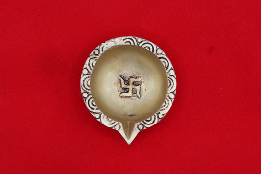 Brass diya seen from above, swastik in the well