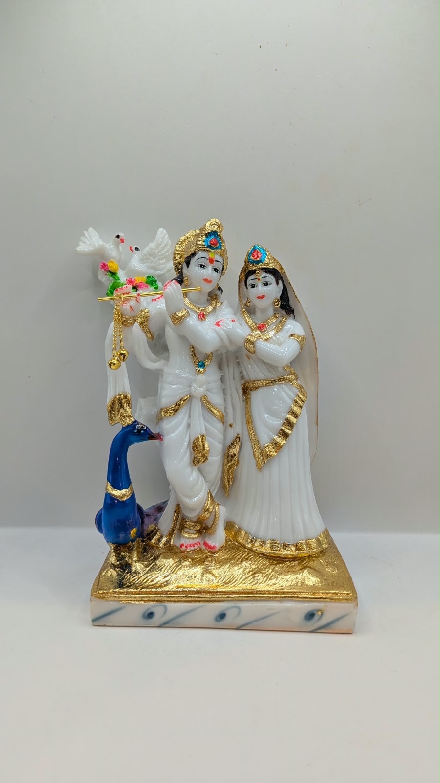 White and gold Radha Krishna statue with peacock, front view
