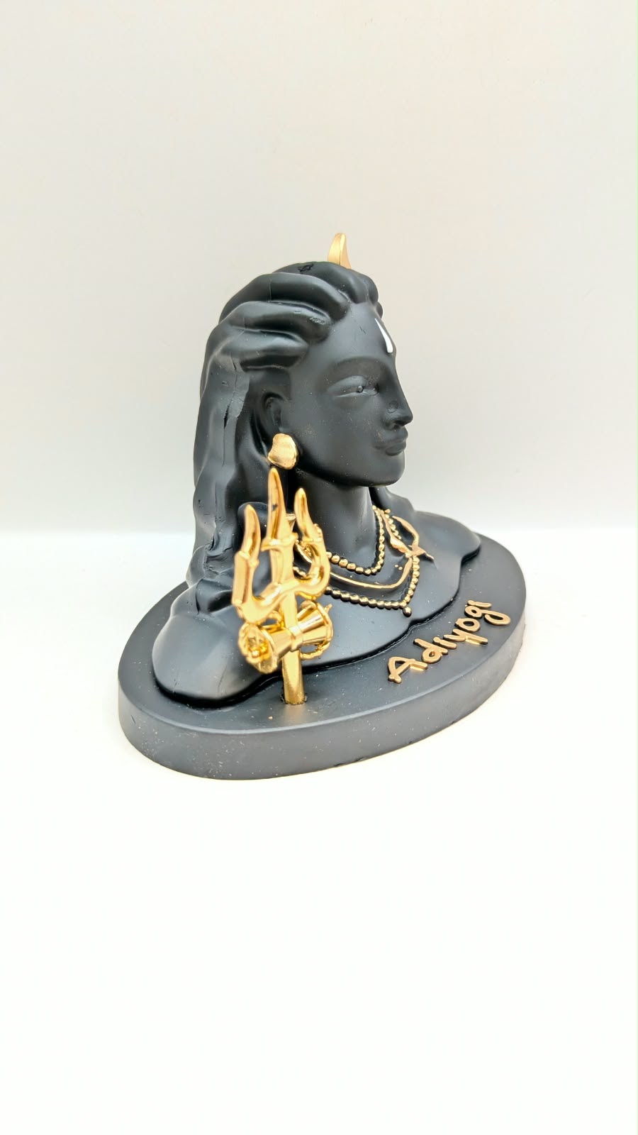 Black Adiyogi Shiva statue with gold trishul, side view
