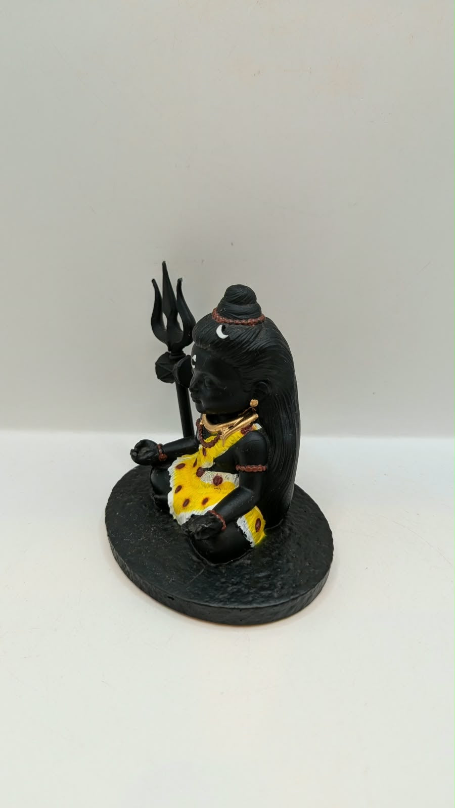 Small black sitting Shiva statue with trishul, other side view