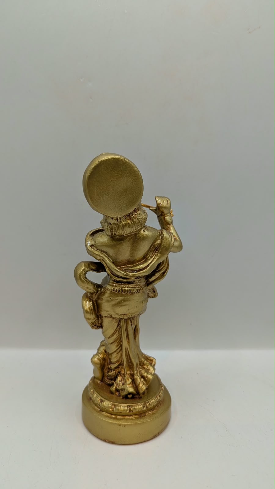Gold Lord Krishna statue with flute, back view
