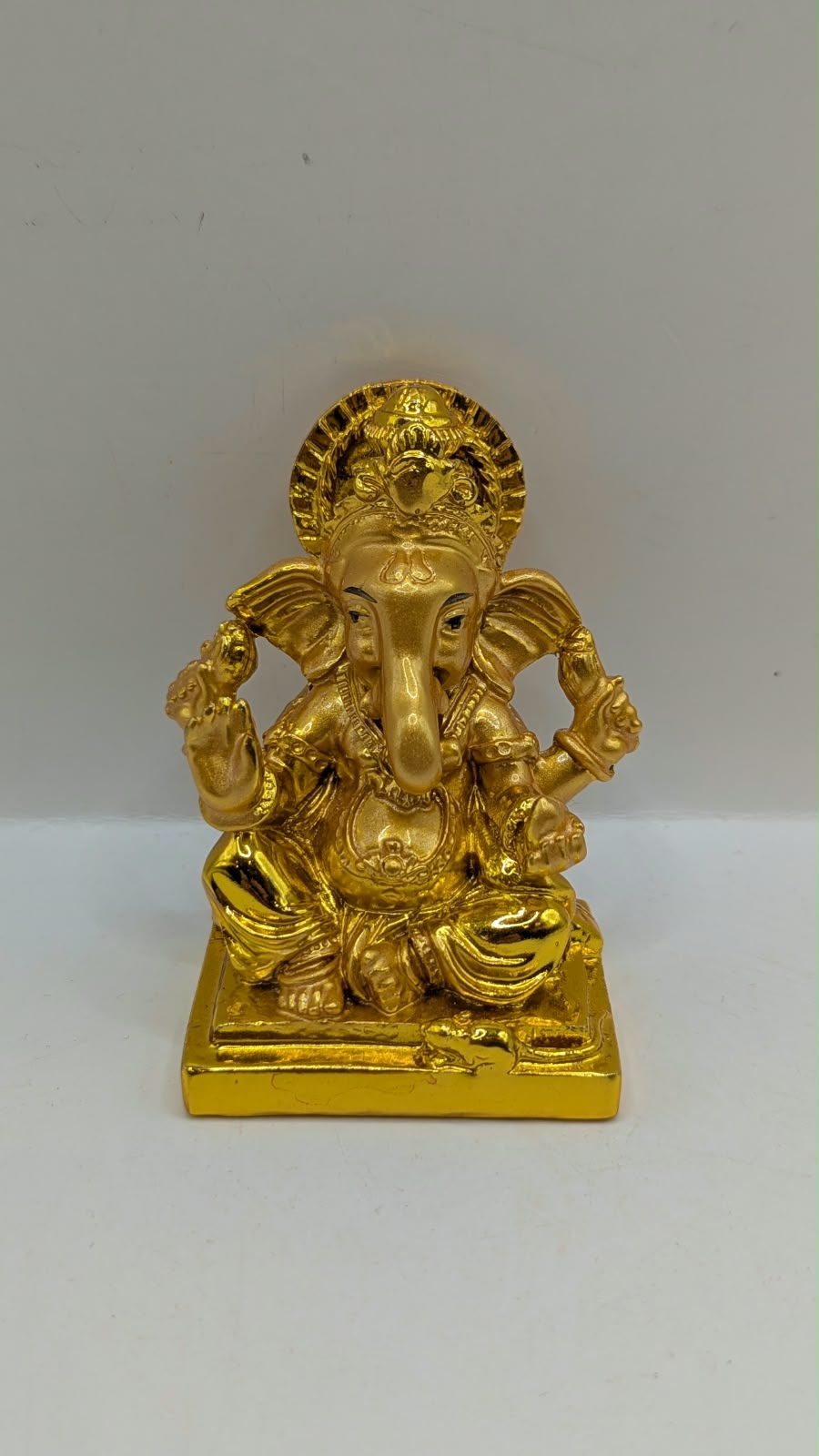 Gold Ganesh statue with round halo, front view
