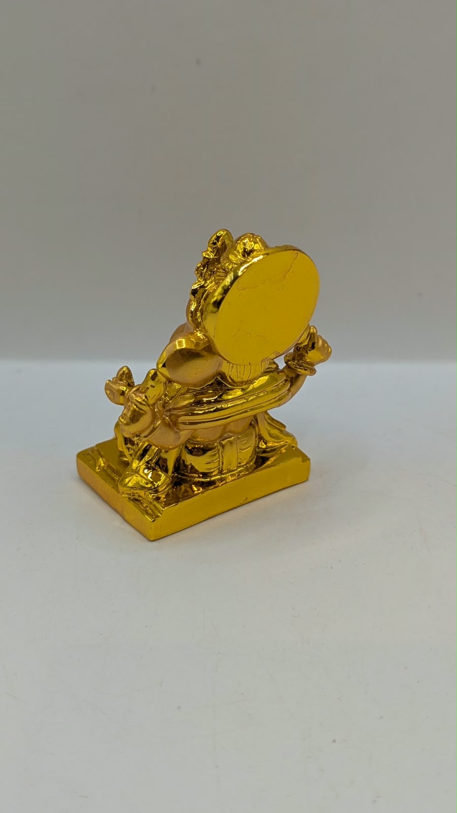 Gold Ganesh statue with round halo, back view