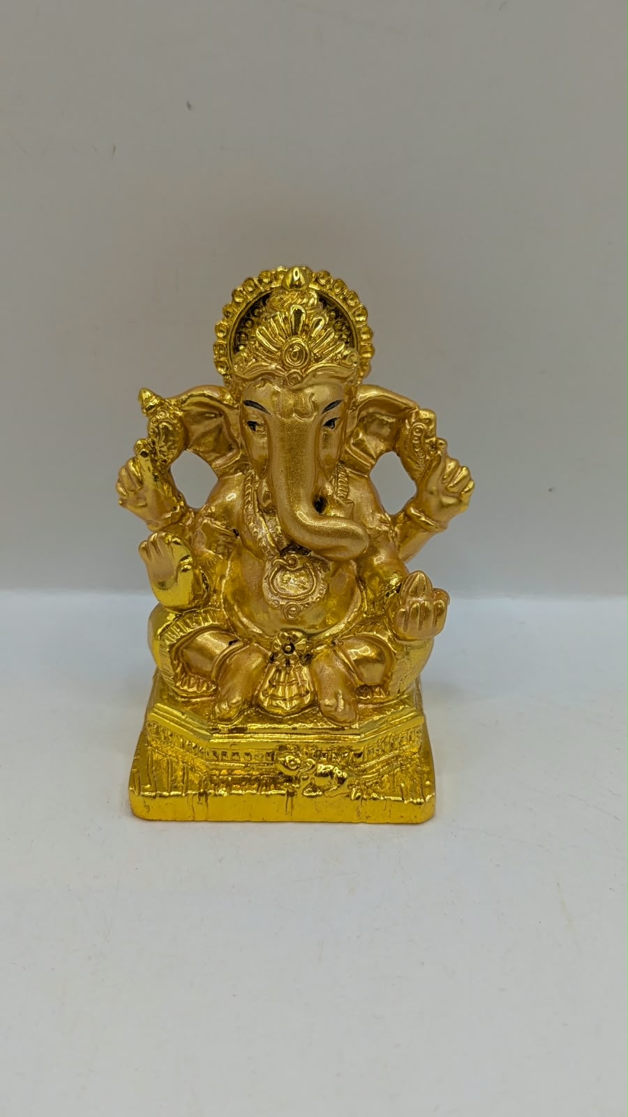 Gold Ganesh statue with crown and halo, front view