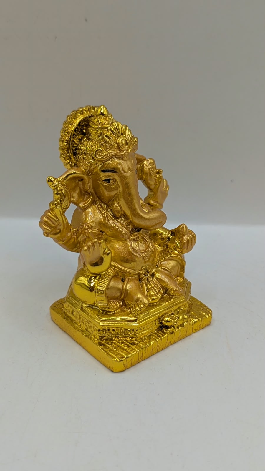 Gold Ganesh statue with crown and halo, side view
