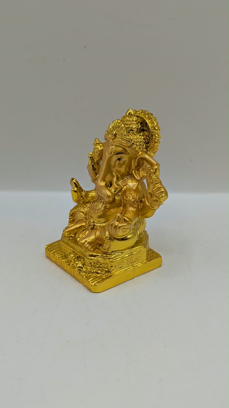 Gold Ganesh statue with crown and halo, other side view