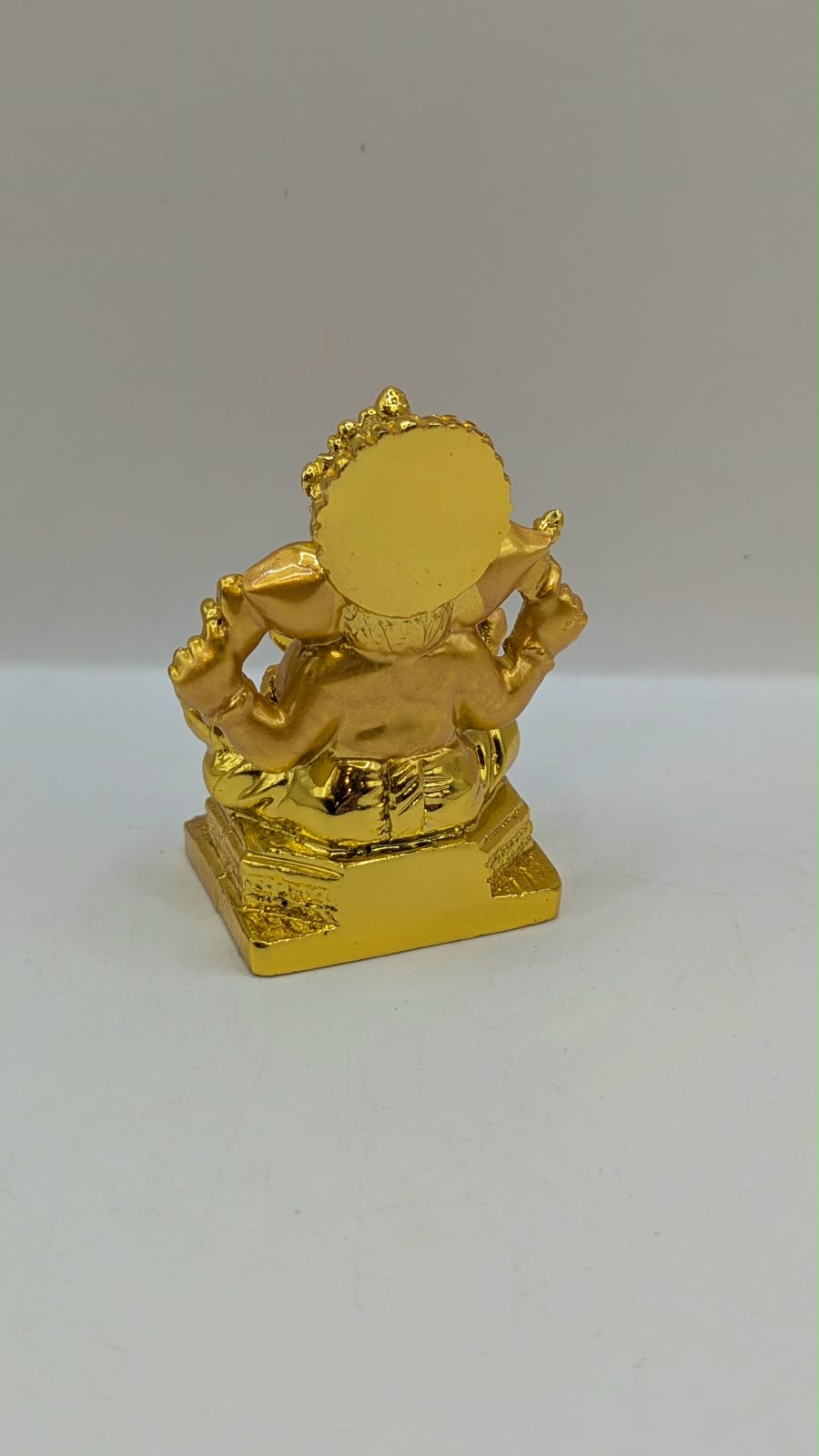 Gold Ganesh statue with crown and halo, back view