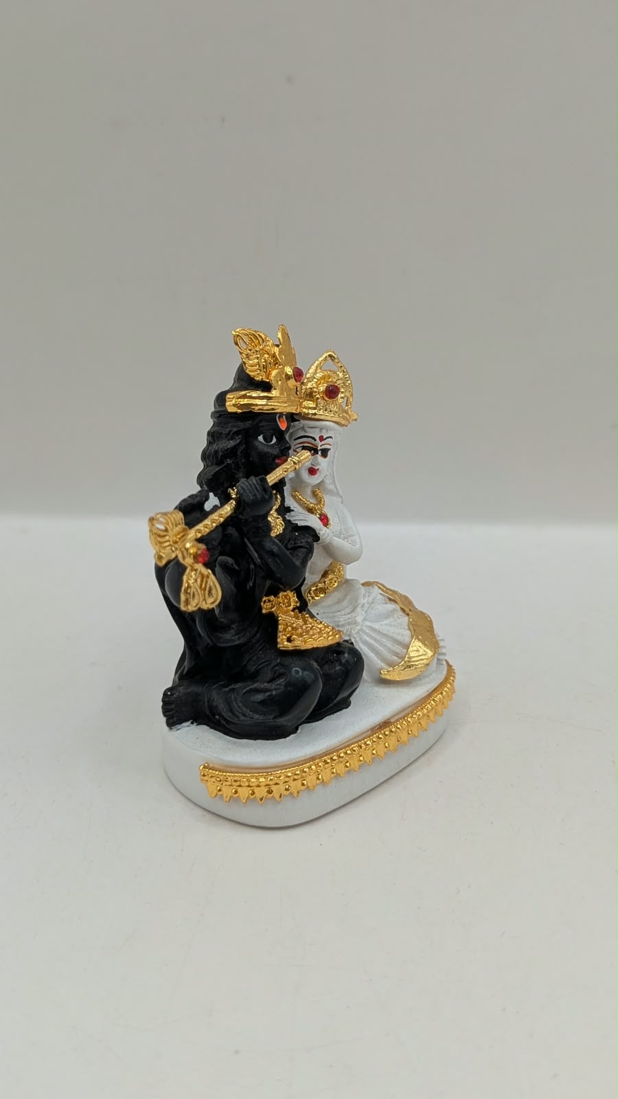 Black and white Radha Krishna statue with gold, side view
