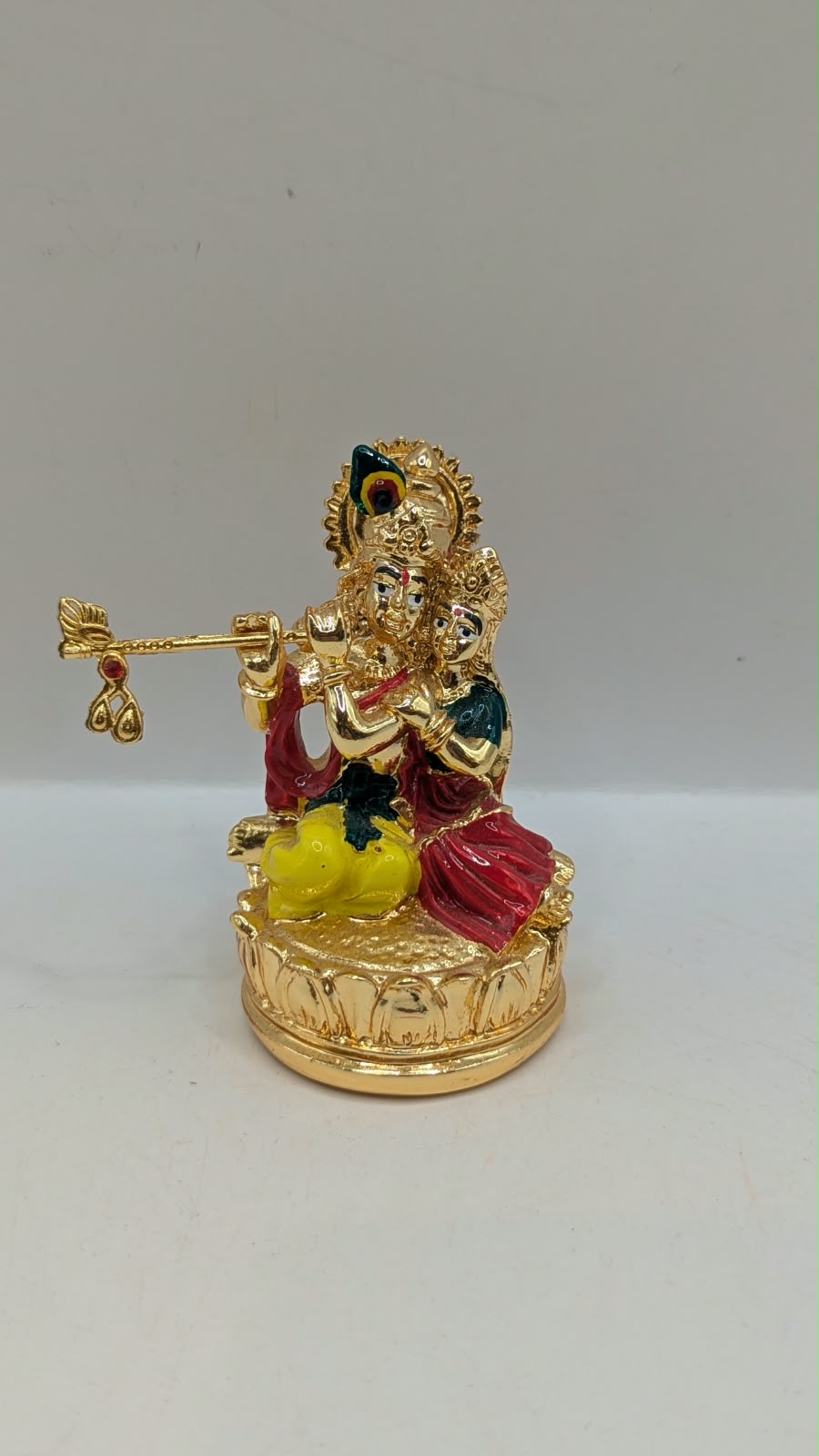 Gold Radha Krishna statue on a lotus base, front view