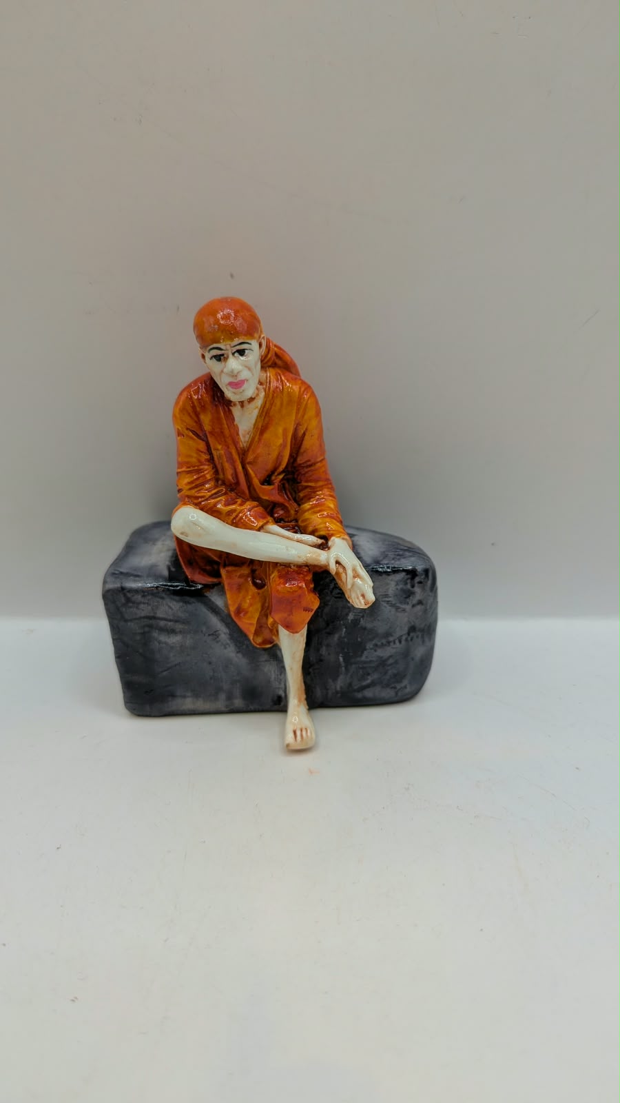 Small Sai Baba statue on grey rock, front view