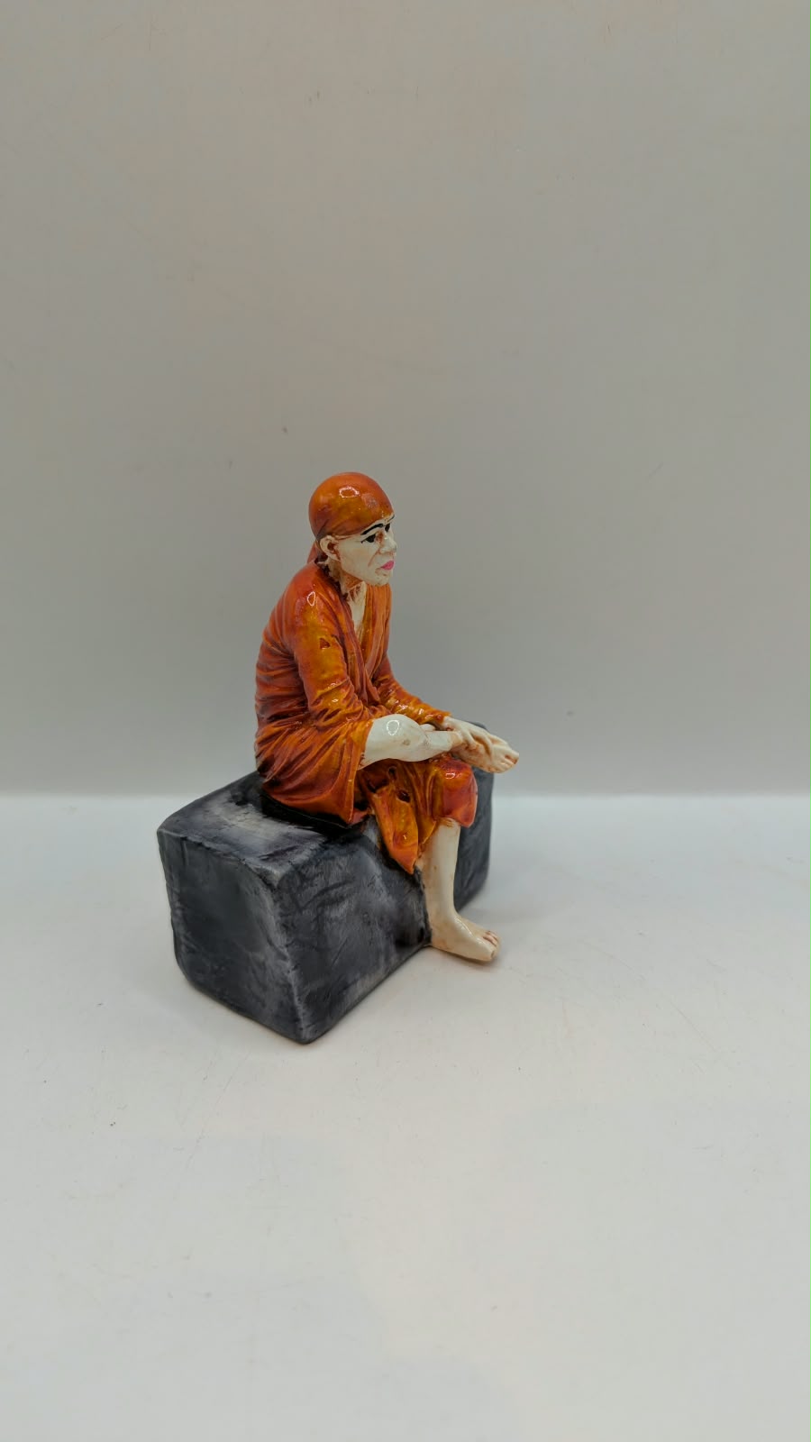 Small Sai Baba statue on grey rock, side view