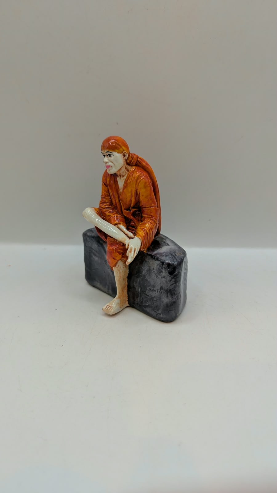 Small Sai Baba statue on grey rock, other side view
