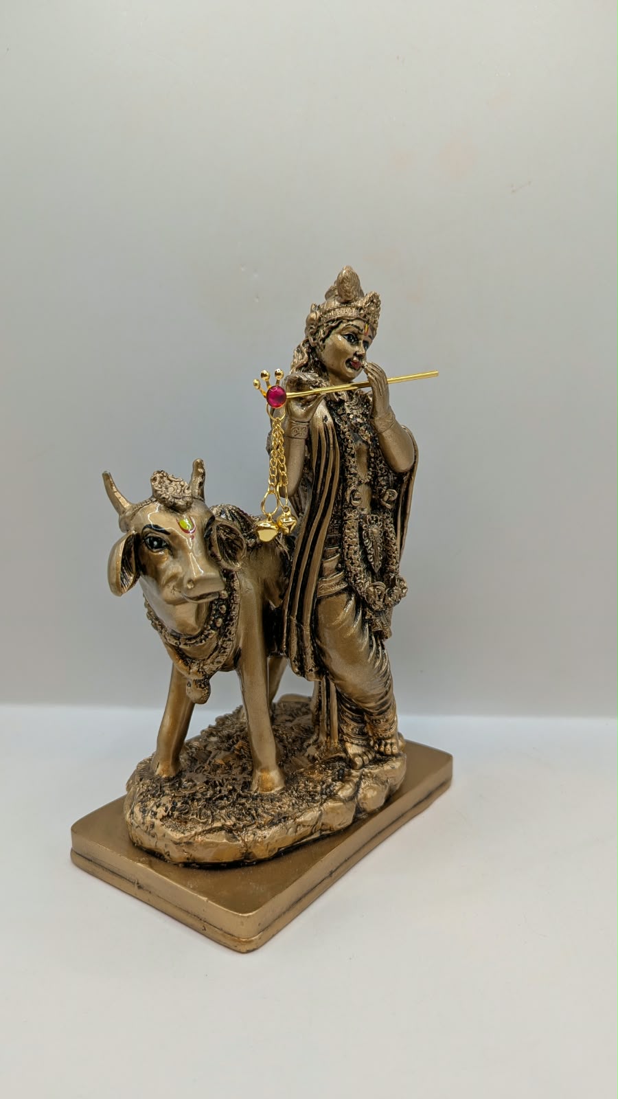 Antique gold Krishna with cow statue, side view