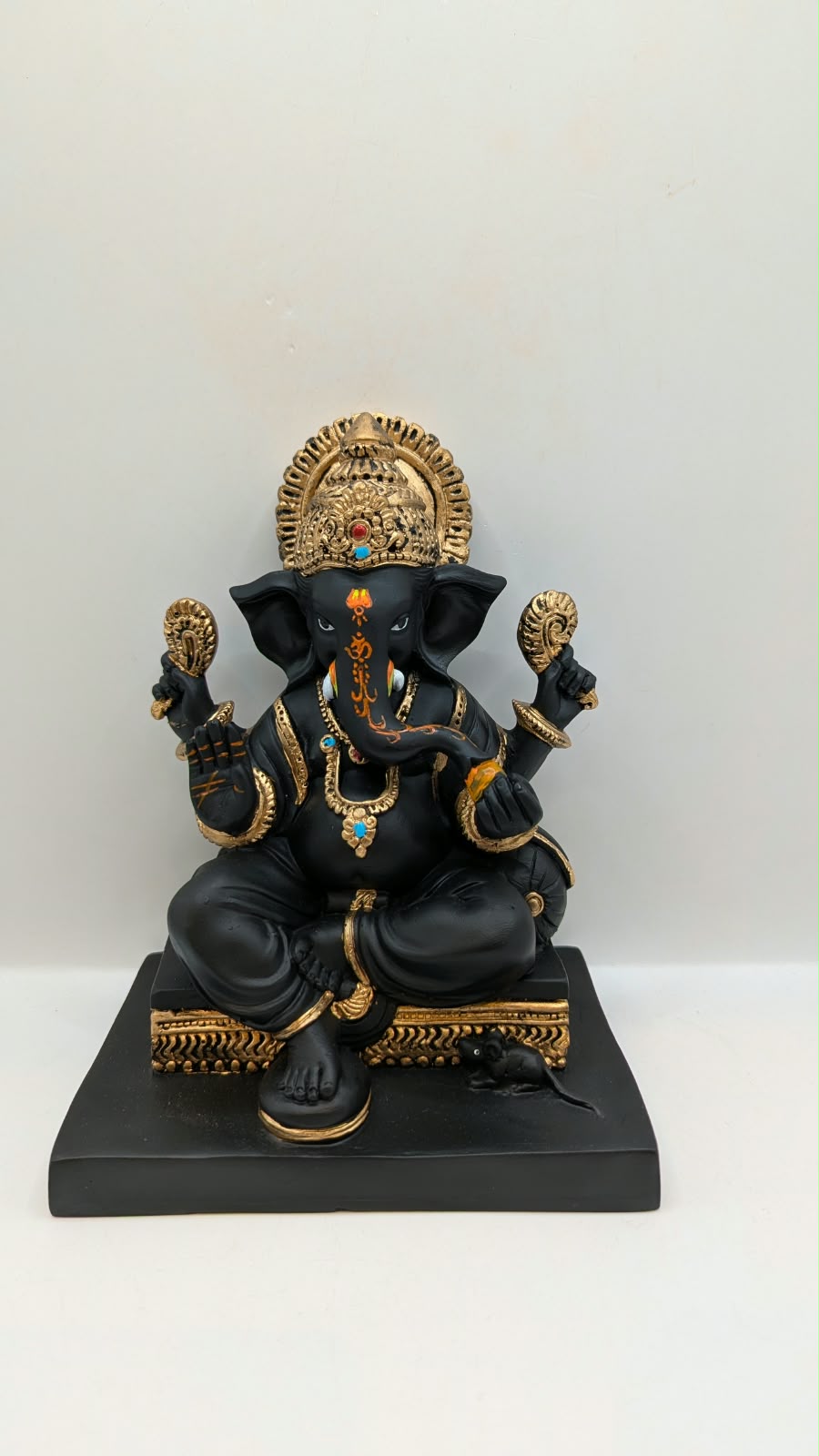 Black and gold Ganesh statue on square base, front view