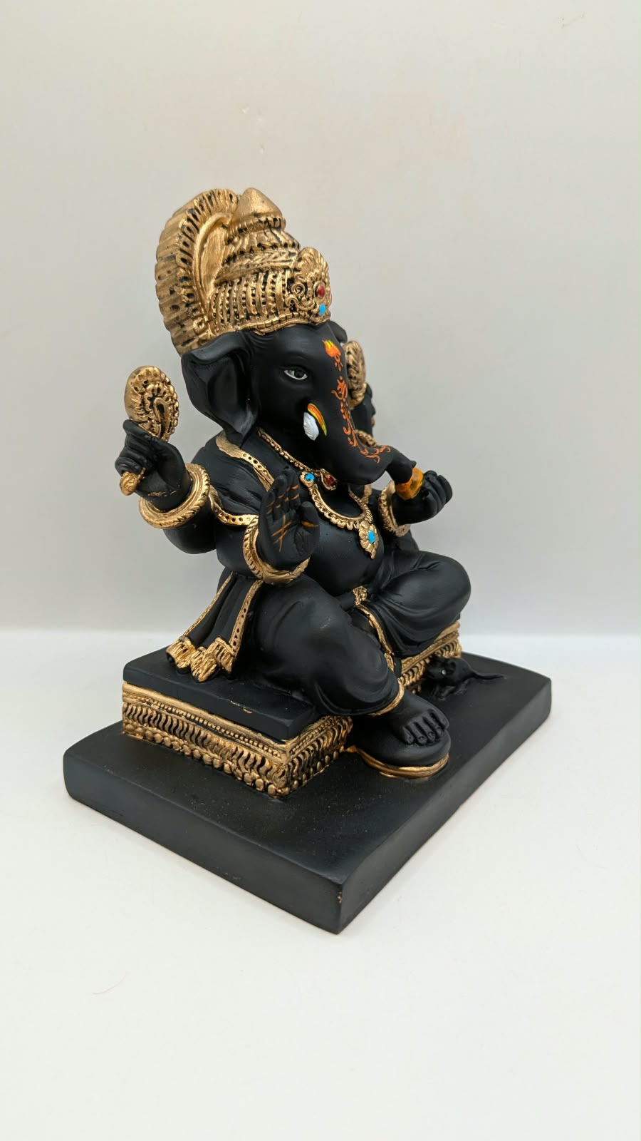 Black and gold Ganesh statue on square base, side view