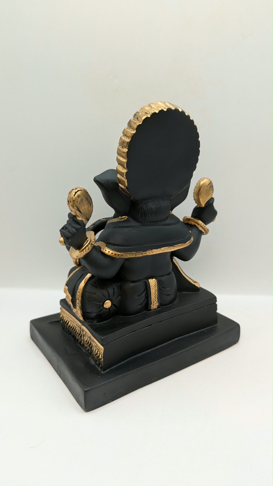 Black and gold Ganesh statue on square base, back view