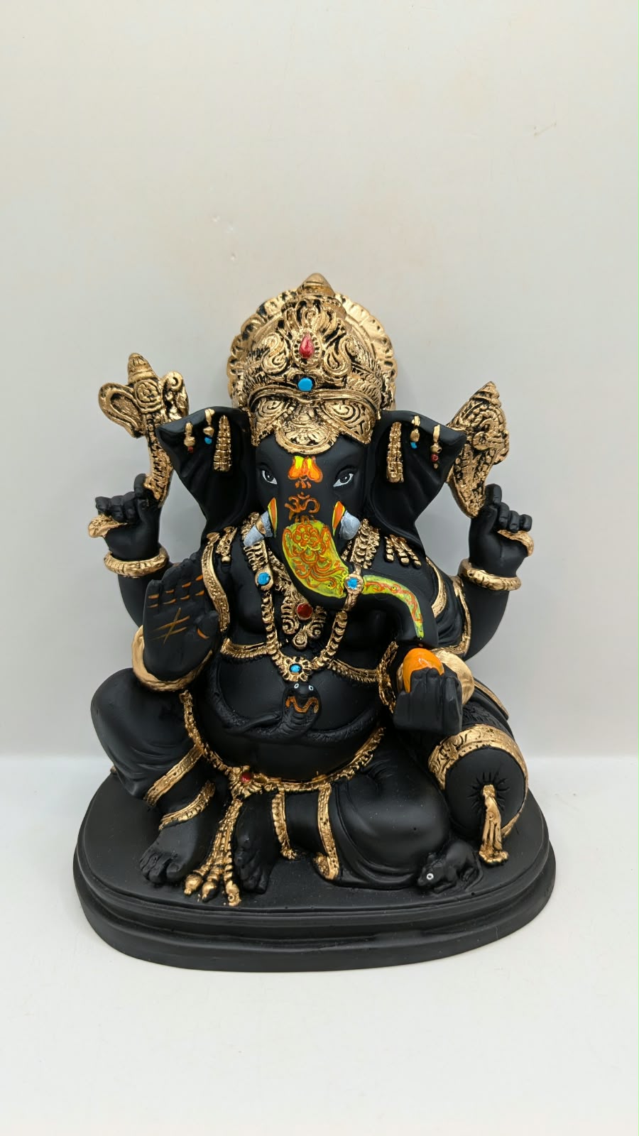 Black and gold Ganesh statue with crown, front view