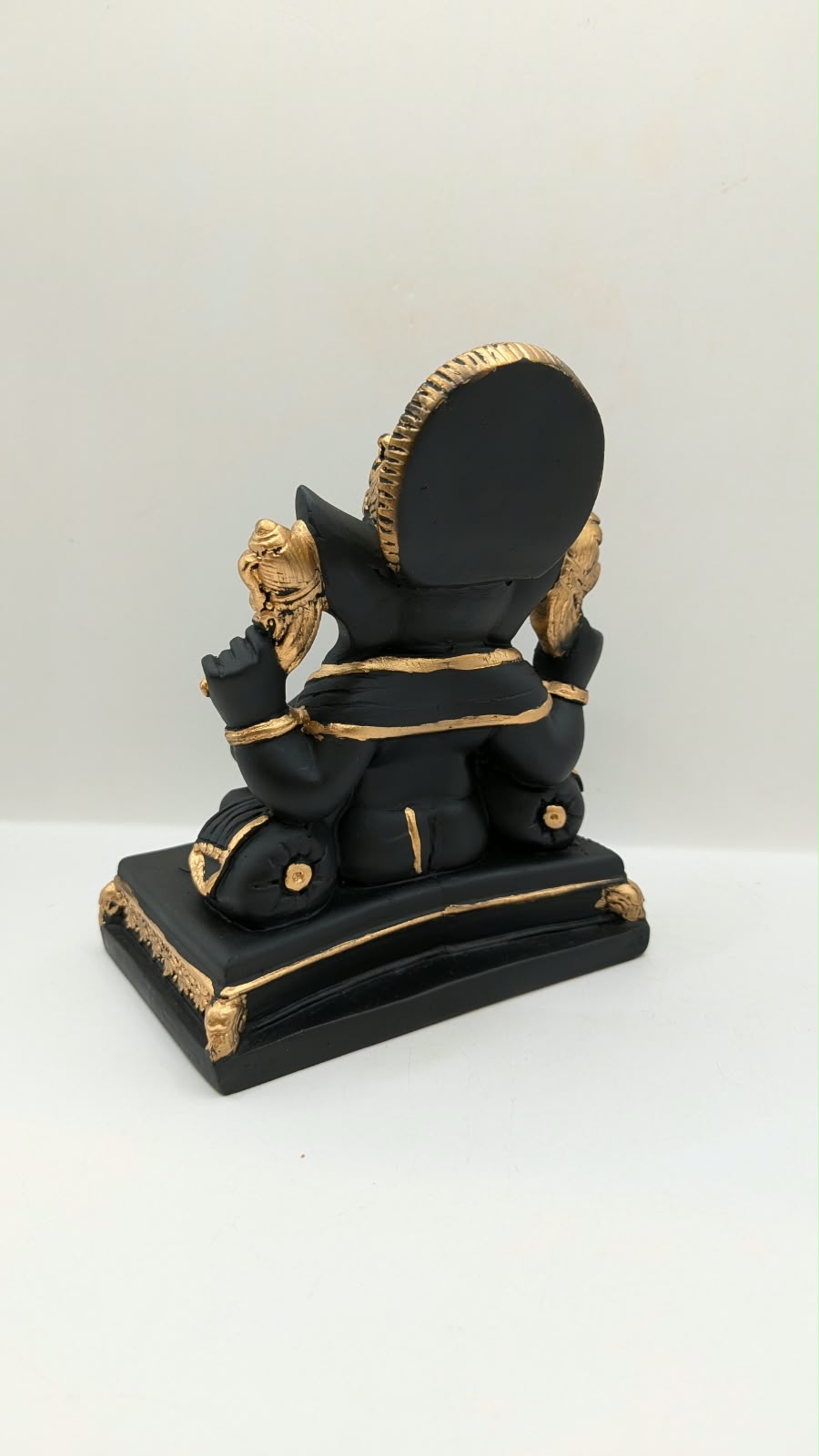 Black and gold Ganesh statue on throne base, back view
