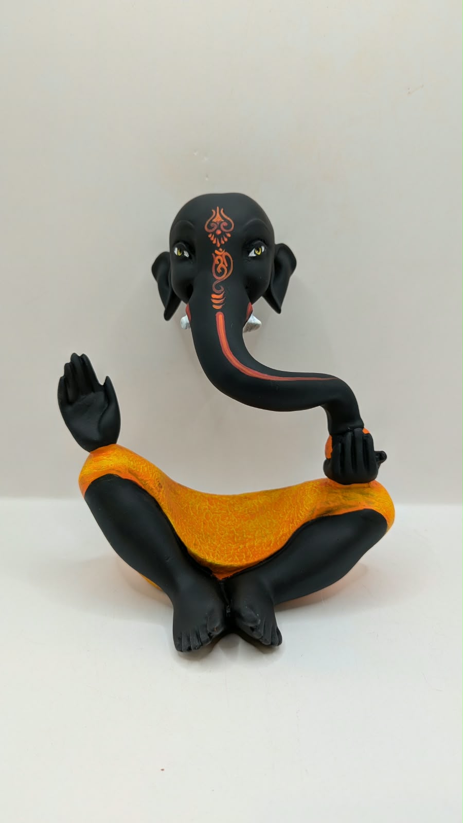 Modern black Ganesh statue with orange dhoti, front view
