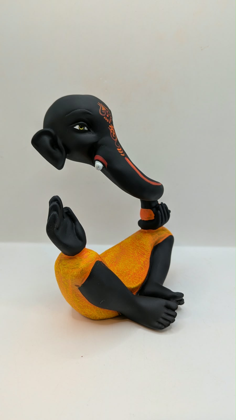 Modern black Ganesh statue with orange dhoti, side view