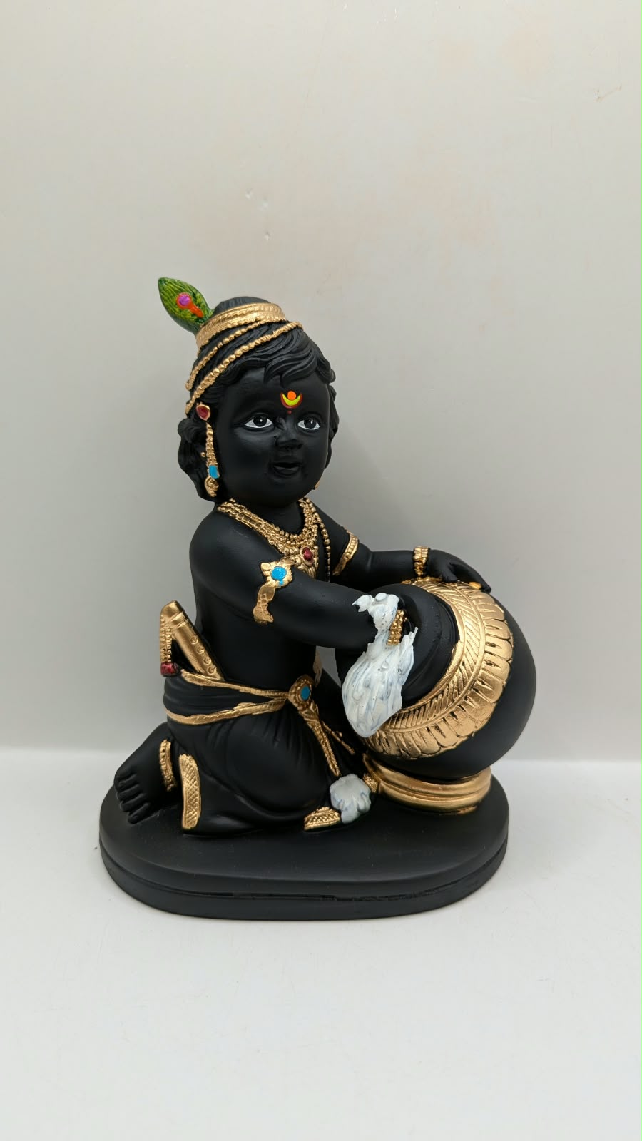 Black and gold baby Krishna statue with butter pot, front view